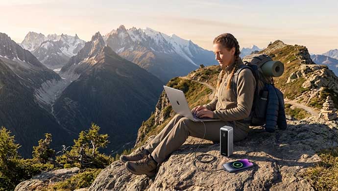 A women traveler usting anker prime power bank on the hill.